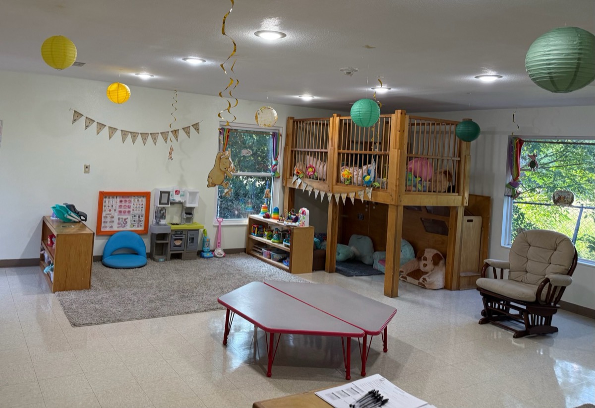 Classroom with a wooden loft, rocking chair, and play areas