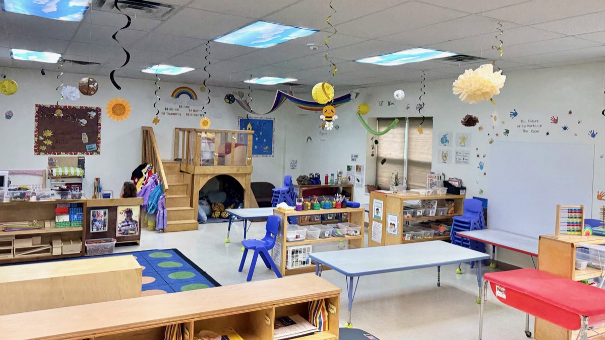 Preschool classroom with tables, learning centers, and a reading loft