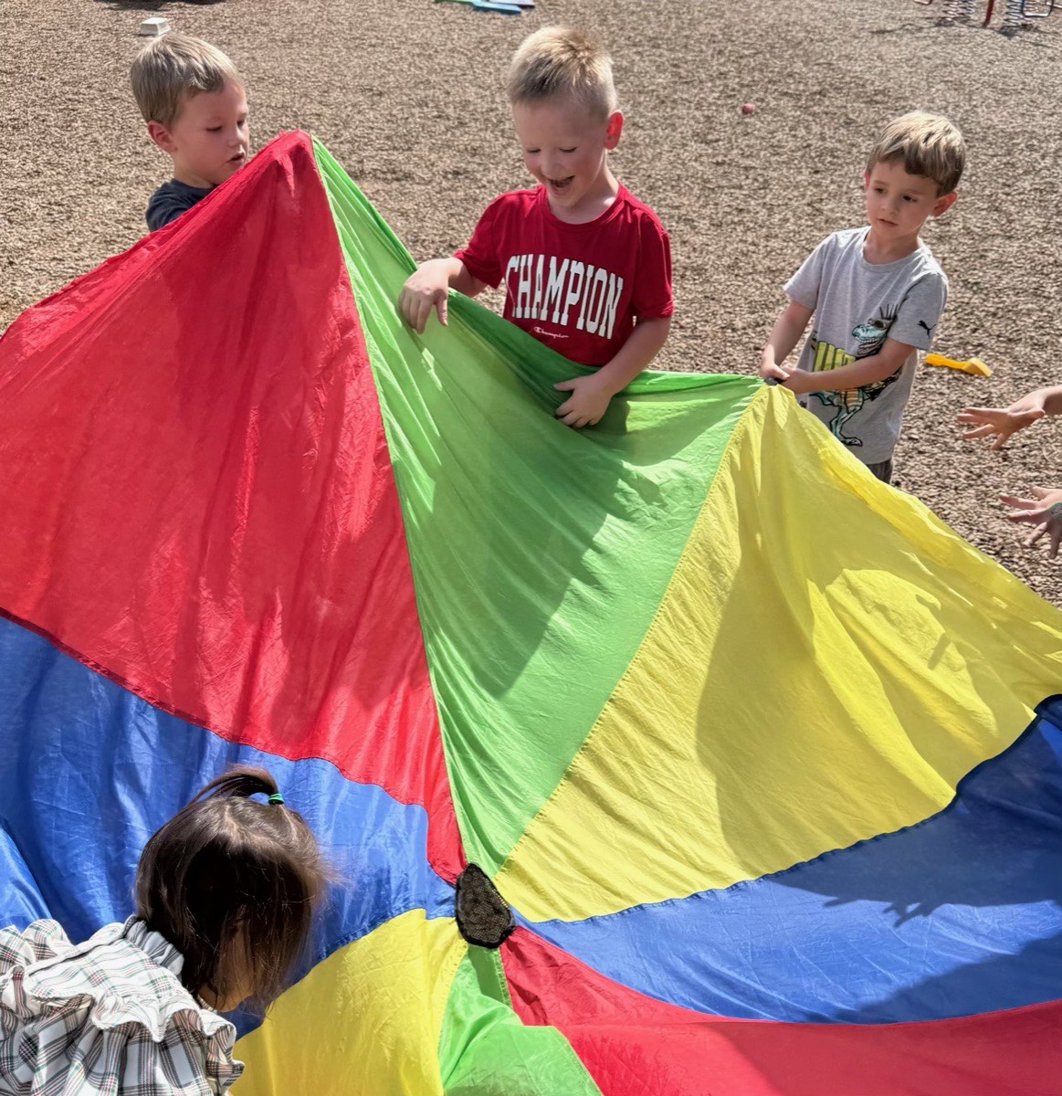 Children playing with a rainbow parachute on the GGK playground
