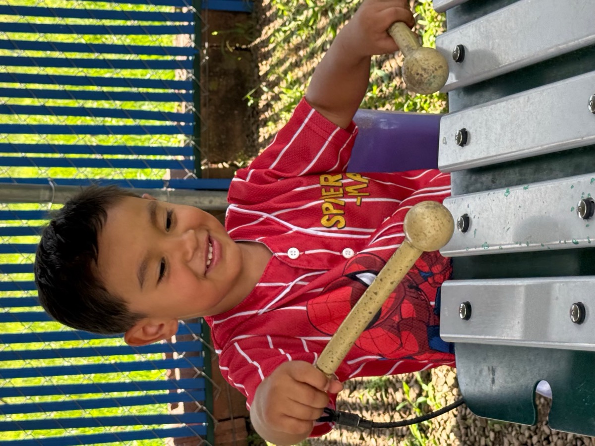 A boy playing a xylophone outside