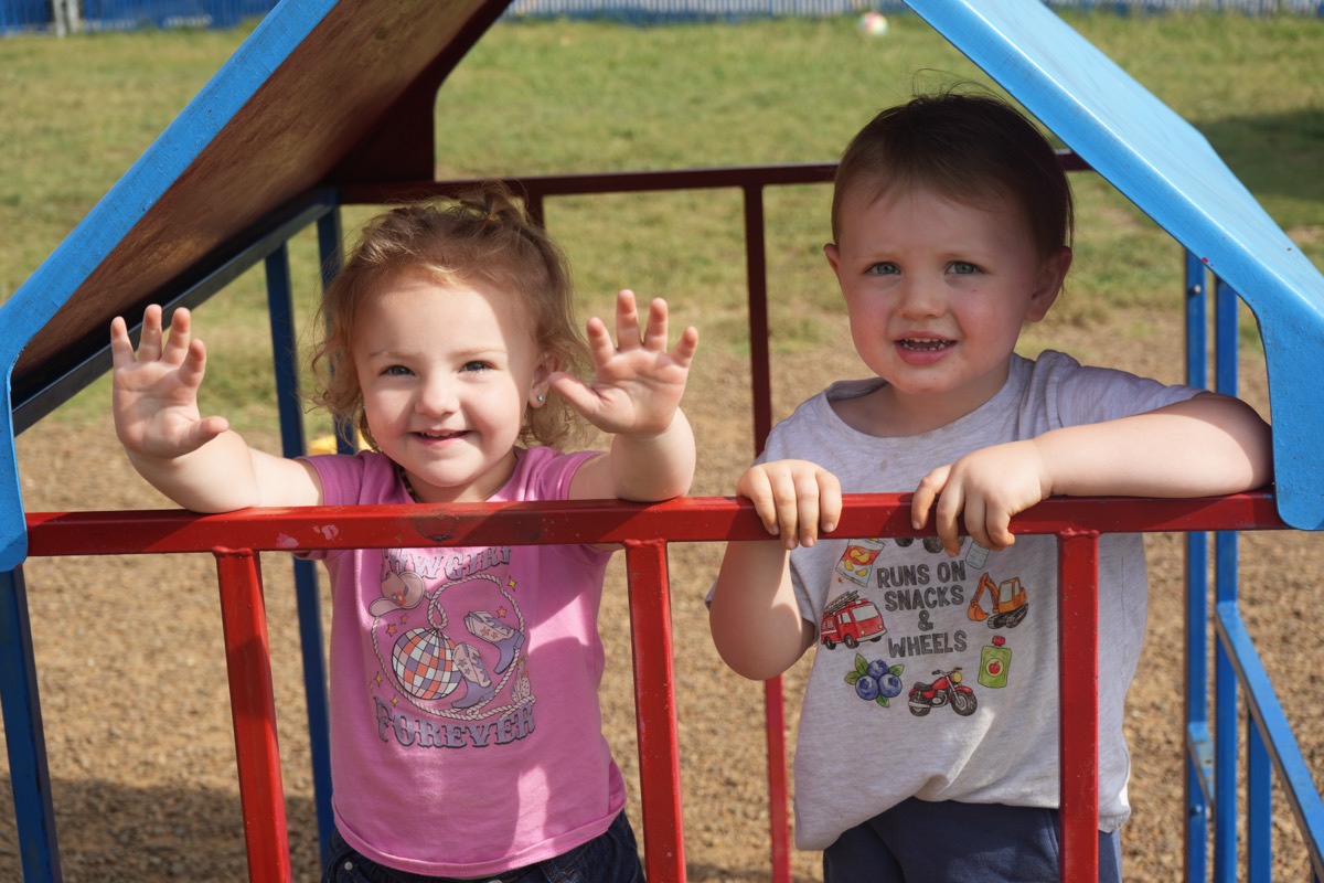 Two children smiling from the top of the climbing structure